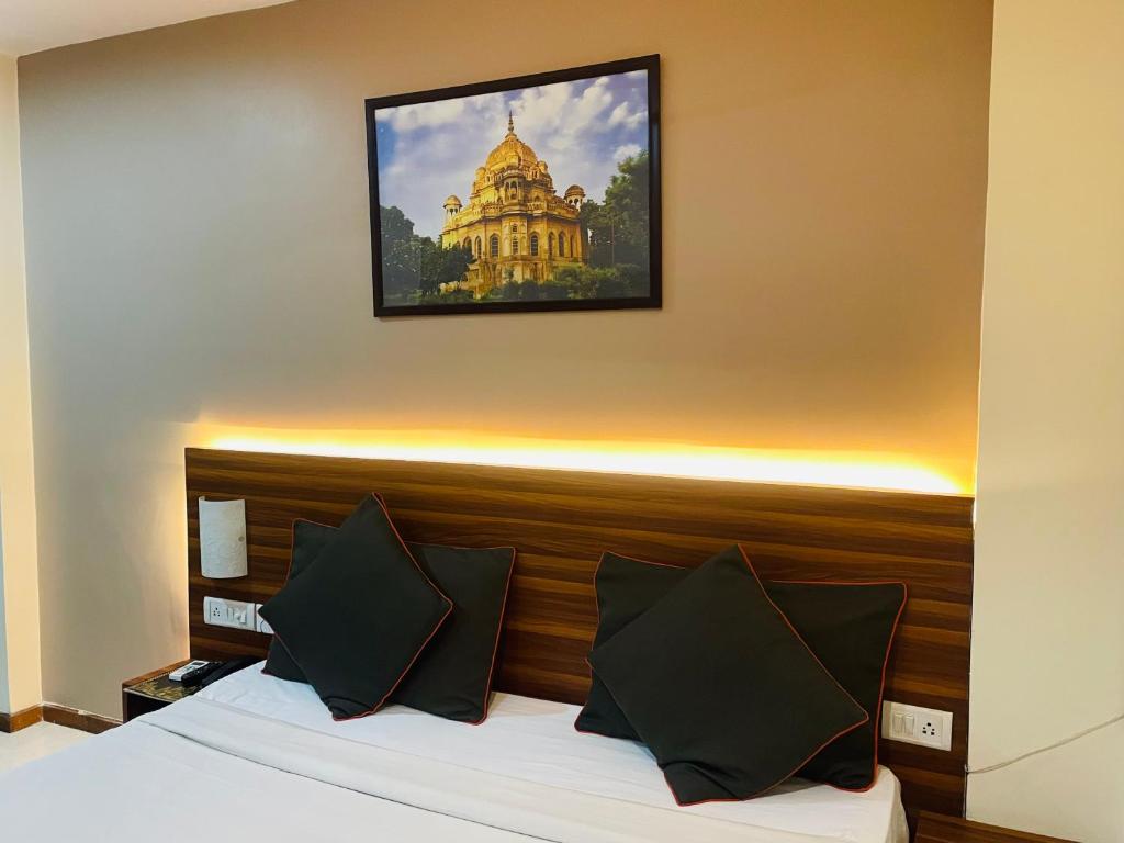勒克瑙THE ROYAL PRESIDENCY INN的酒店客房的墙上设有一张带照片的床。