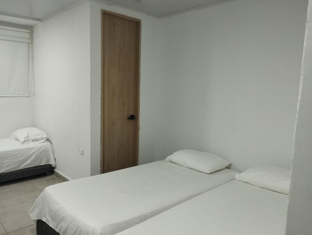 哥伦比亚港Hostal Donde Marle的白色墙壁客房的两张床