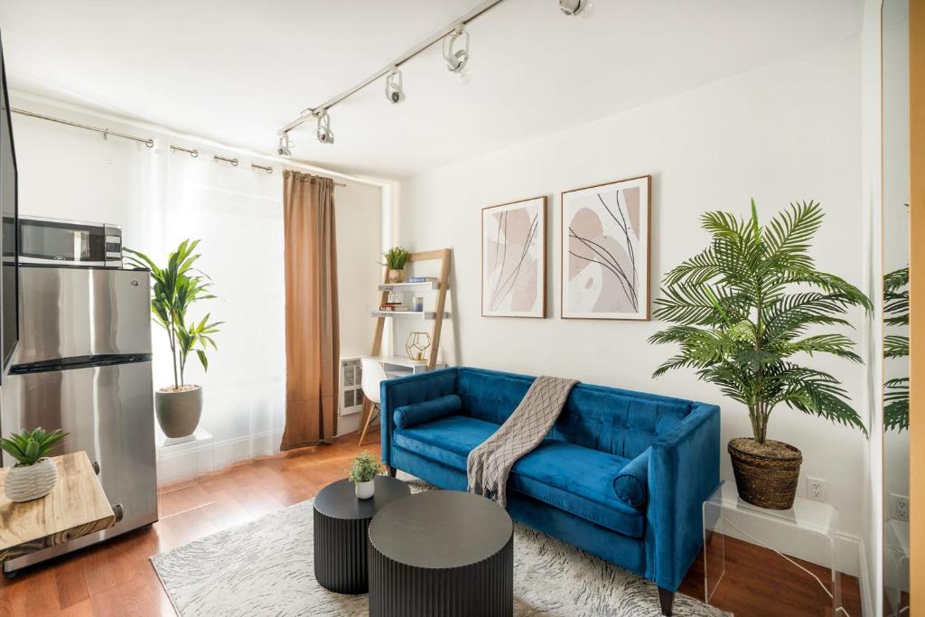 纽约69-4D Trendy Lower East Side 1B BRAND NEW的客厅配有蓝色的沙发和盆栽植物