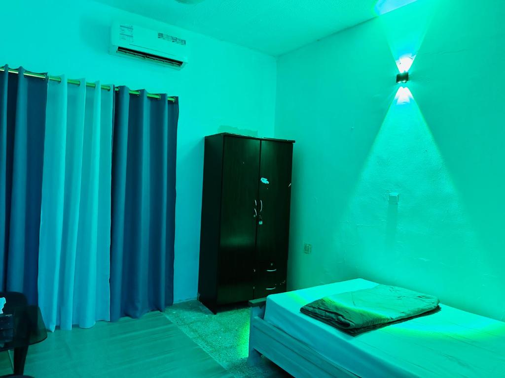 沙迦Room for rent的客房设有床和带蓝色灯的橱柜。