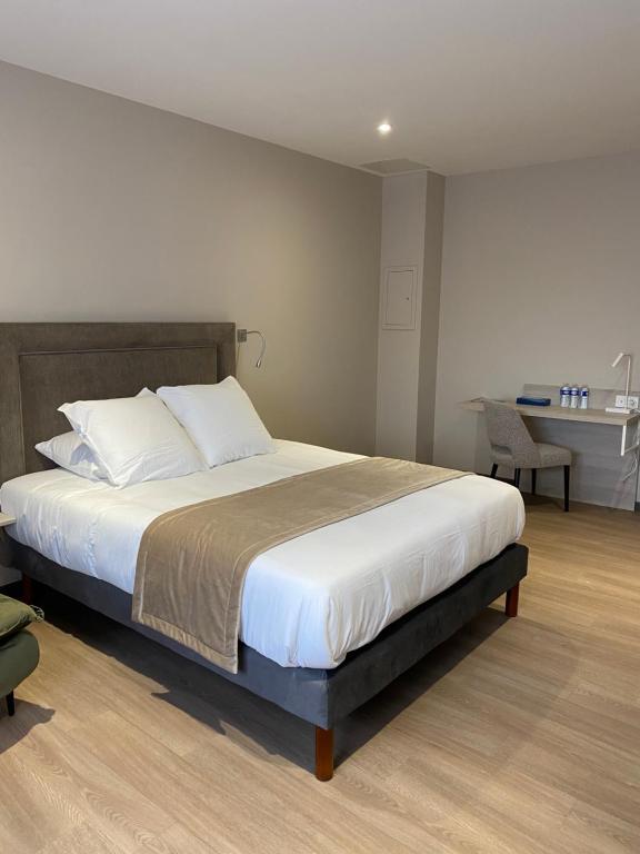 诺让-巴西尼Hôtel du Commerce-restaurant au Couteau的一间卧室配有一张大床和一张书桌
