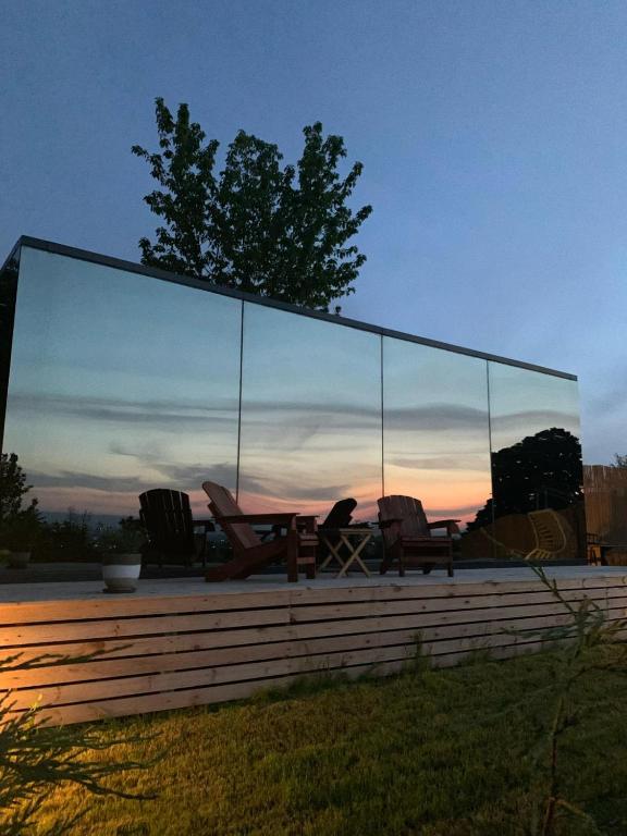 科贾埃利Perspective Mirror House的一个带椅子和一张桌子的玻璃温室,享有日落美景