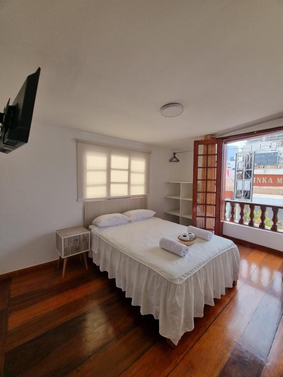 利马Hostel Prada的一间卧室配有一张带白色床单的床和一扇窗户。