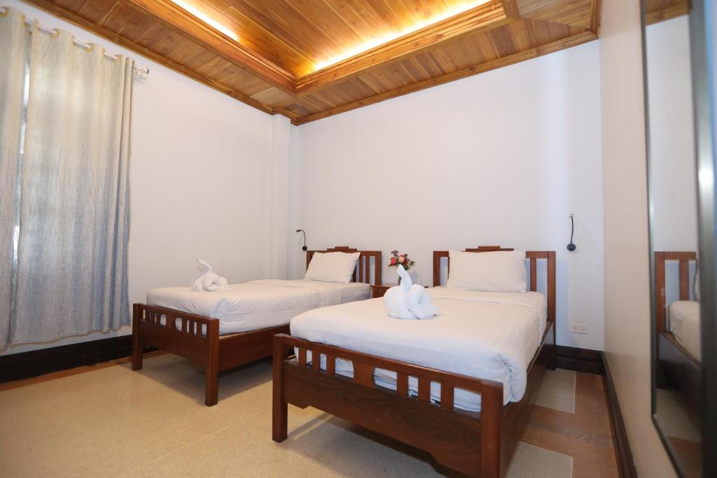 琅勃拉邦Villa KiengKham晶康民宿的配有白色床单的客房内的两张床