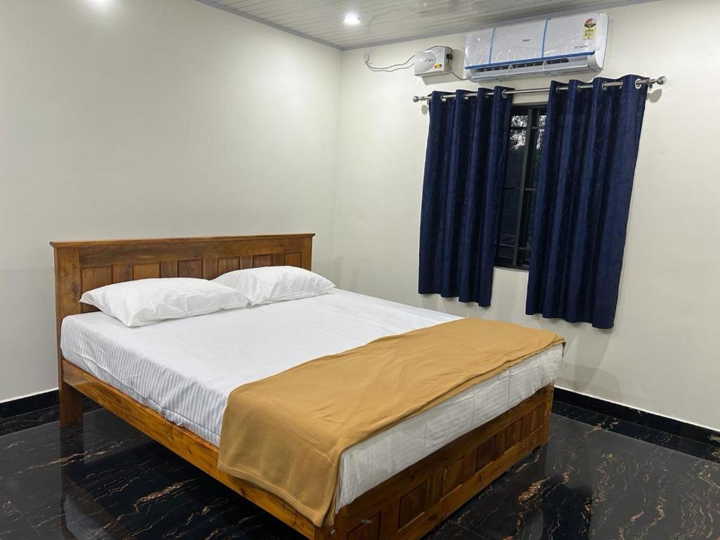 戈卡尔纳Yashovana Nature Stay Gokarna的一间卧室配有一张带蓝色窗帘的大床