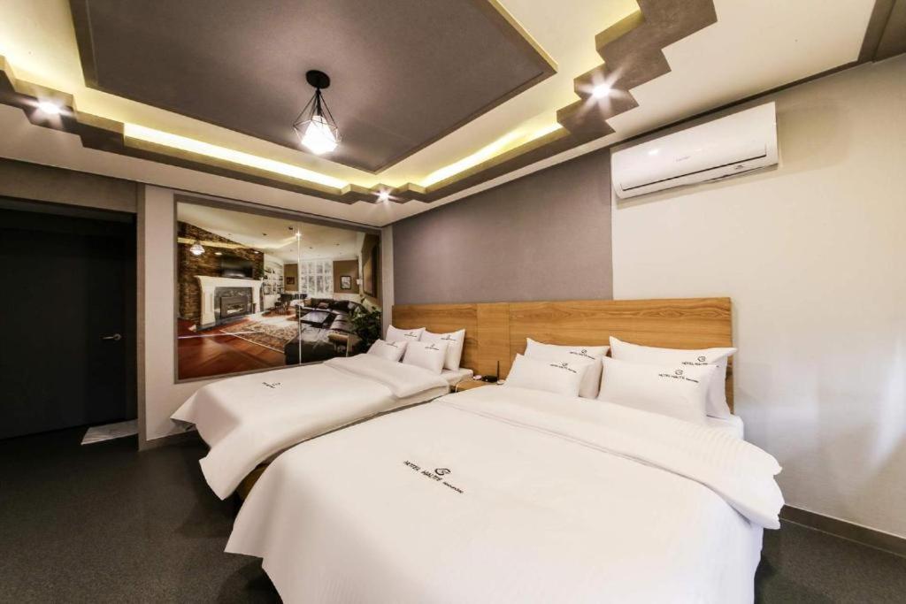 釜山Haute Hotel的一间卧室配有两张带白色床单的床