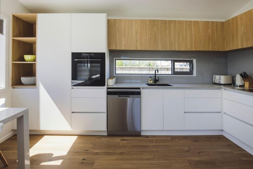 新普利茅斯Lovely on Lismore的厨房配有白色橱柜和不锈钢用具