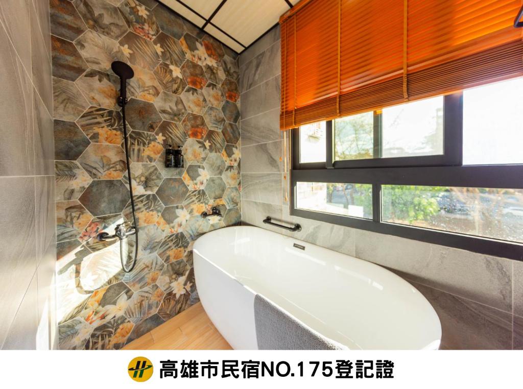 高雄自由宿-盐埕馆的带浴缸的浴室和石墙