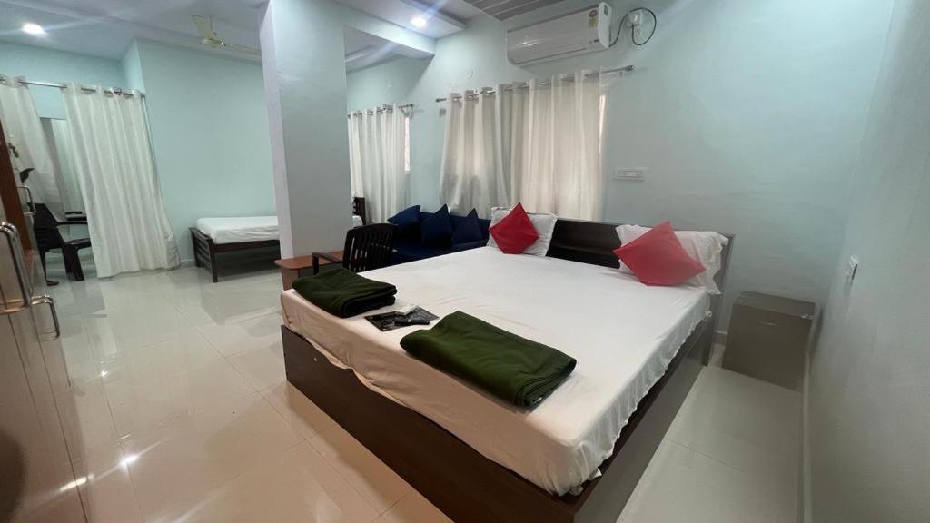 海得拉巴Brundavan的一间卧室配有一张带红色和绿色枕头的大床