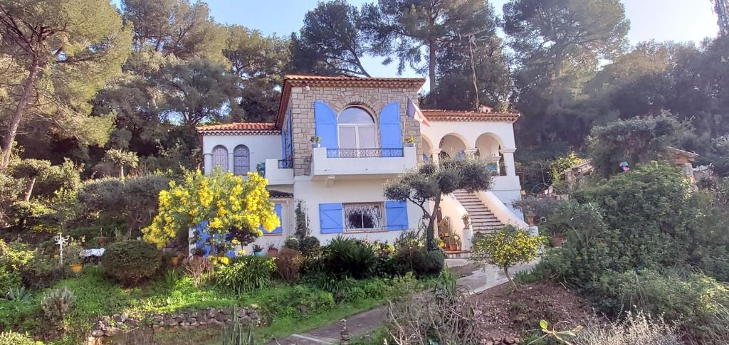 昂蒂布Magnifique "Gite de la Garoupe" au Cap d'Antibes à 300m des plages的蓝色百叶窗和树木的房子