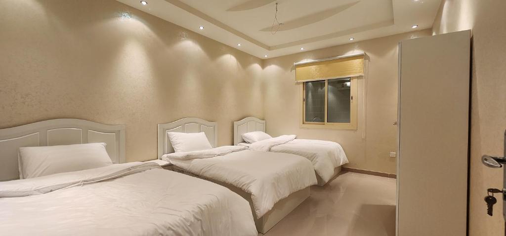 麦加شقة بثلاث غرف نوم وصالة的一间卧室设有两张带白色床单的床和窗户。