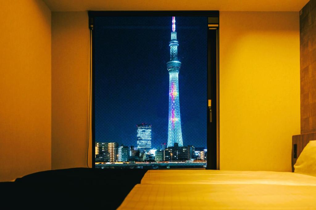 东京stayme THE HOTEL Asakusa Riverside的一间卧室,晚上可欣赏到艾菲尔铁塔的景色