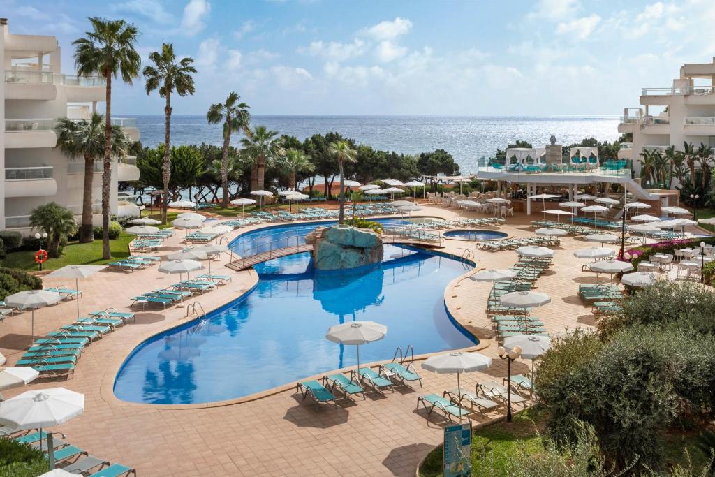 圣埃乌拉利亚热带花园公寓式酒店的享有带椅子和遮阳伞的度假村游泳池的顶部景致
