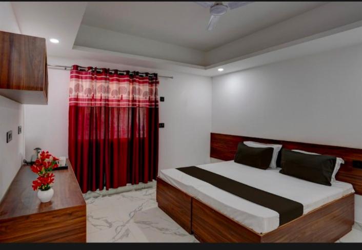大诺伊达The Simran suites的一间卧室配有一张带红色窗帘的大床