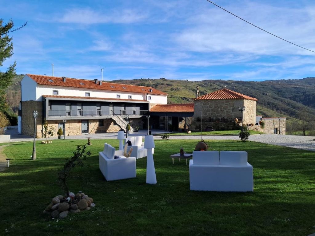 瓜尔达Alqueiturismo - Casas de Campo的建筑前草上带白色椅子的建筑