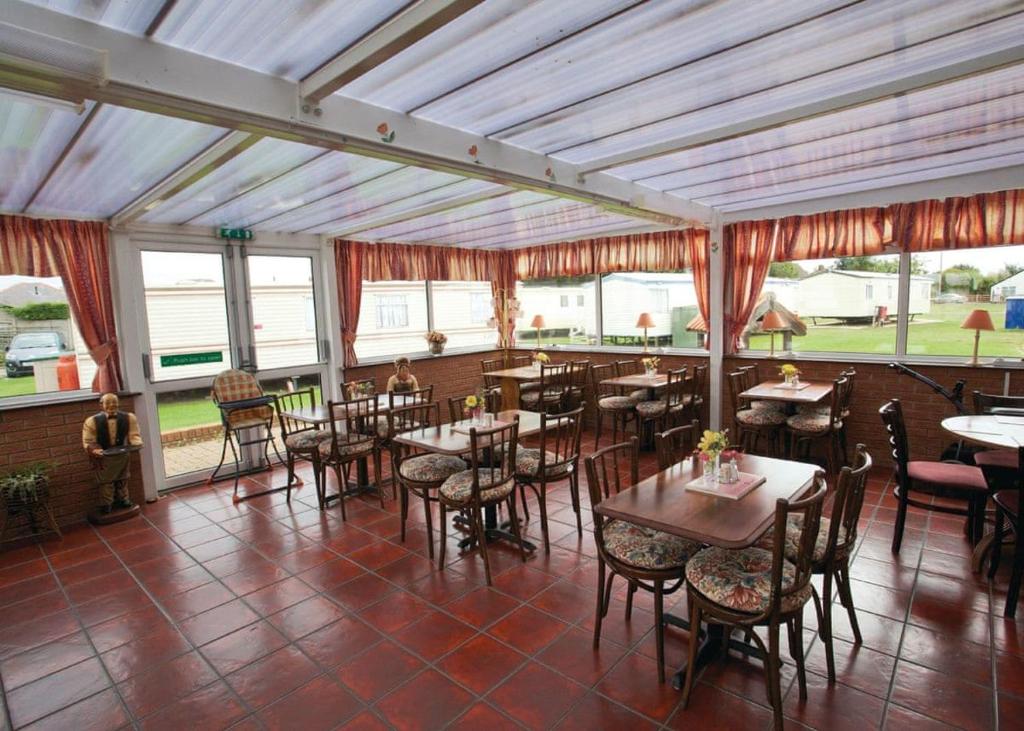 梅布尔索普Towervans Caravan Park的餐厅设有桌椅和窗户。