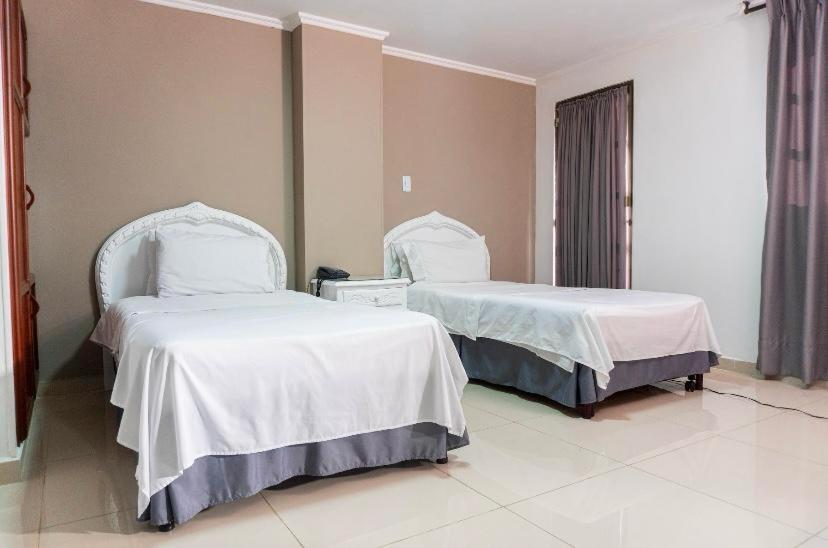 圣罗莎德卡瓦尔Hotel Suite Santa Rosa的配有白色床单的酒店客房内的两张床