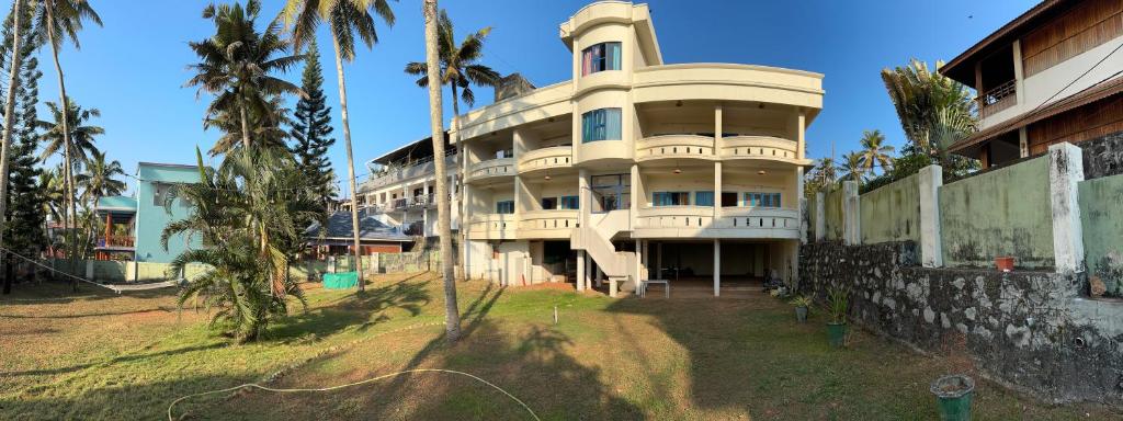 瓦尔卡拉hello beach view resorts的一座高大的建筑,前面有棕榈树