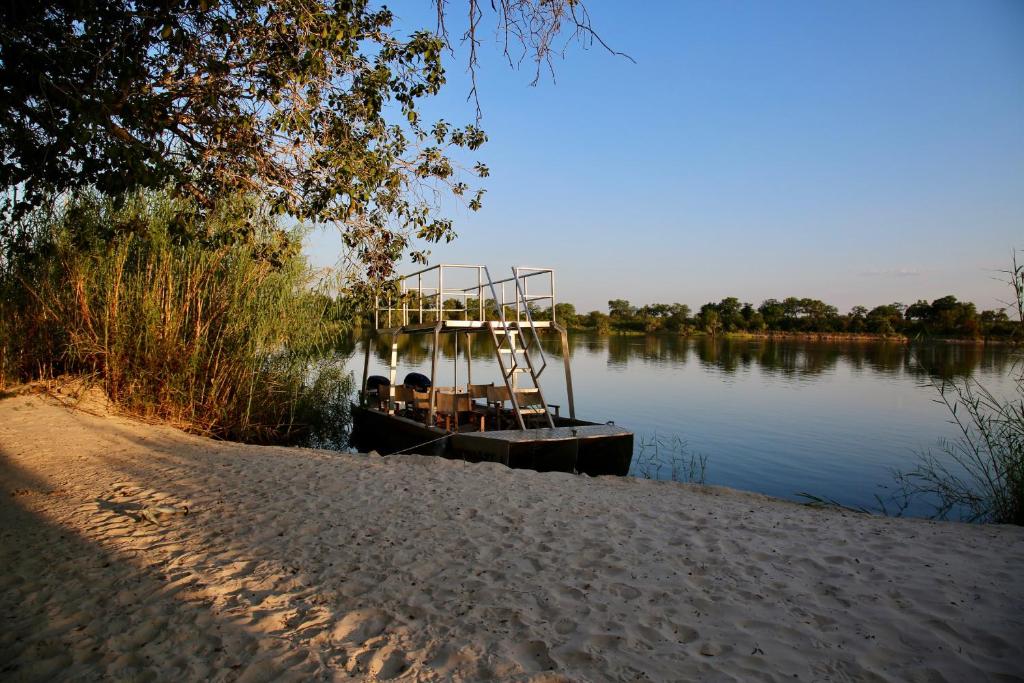 利文斯顿Zambezi Dusk的坐在海滩旁的水面上的船