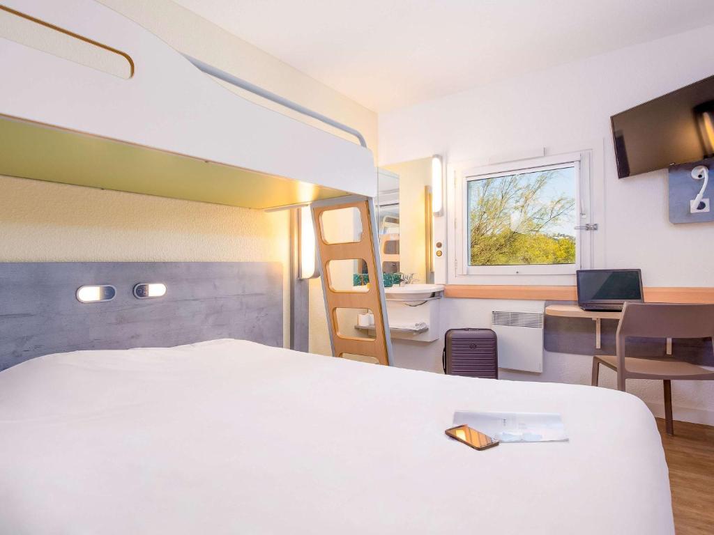 弗雷瑞斯Ibis Budget Fréjus Capitou的一间酒店客房,配有一张白色的床和一张书桌