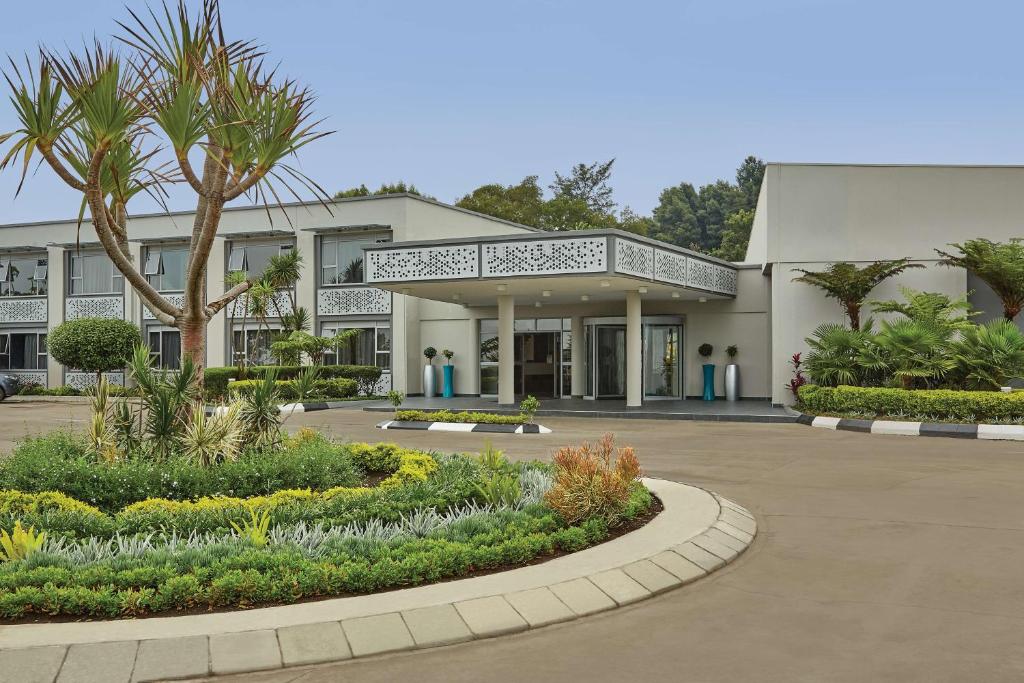 乌姆塔塔Garden Court Mthatha的一座白色的大建筑,前面有一棵棕榈树