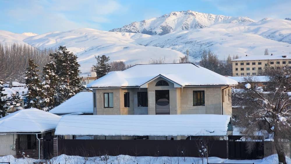 卡拉科尔Karakol Yurt Lodge & Homestay的山地雪覆盖的房子