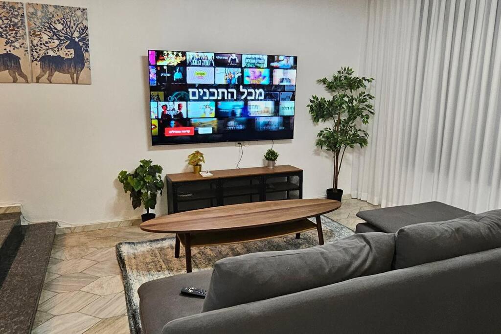 赖阿南纳גדולה ומעוצבת ברעננה的带沙发、桌子和电视的客厅