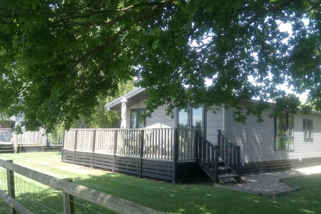 BrooklandRainbow Petty - Pine lodge - Kent countryside的白色的房子,设有门廊和围栏