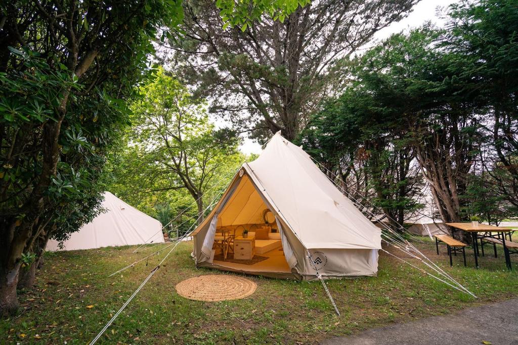 塞洛里奥Kampaoh Playa Troenzo的田野上的两个帐篷,配有桌子和树木