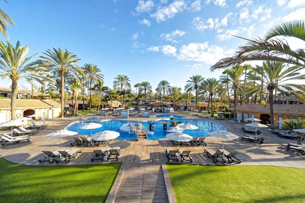 马斯帕洛马斯Suites & Villas by Dunas的一个带椅子和遮阳伞及棕榈树的度假游泳池