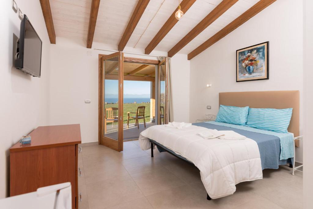 卡斯特尔萨多PARADAISE SUITES SEA VIEW SARDINIA, Bedda Ista的一间卧室配有一张床、一台电视和一个阳台