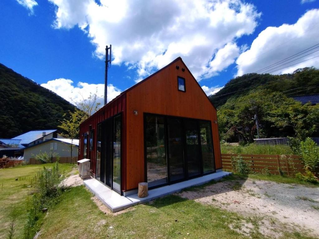 ShōbaraAyu no Sato Park Campsite - Vacation STAY 42240v的一座红色的小房子,在田野上设有玻璃窗
