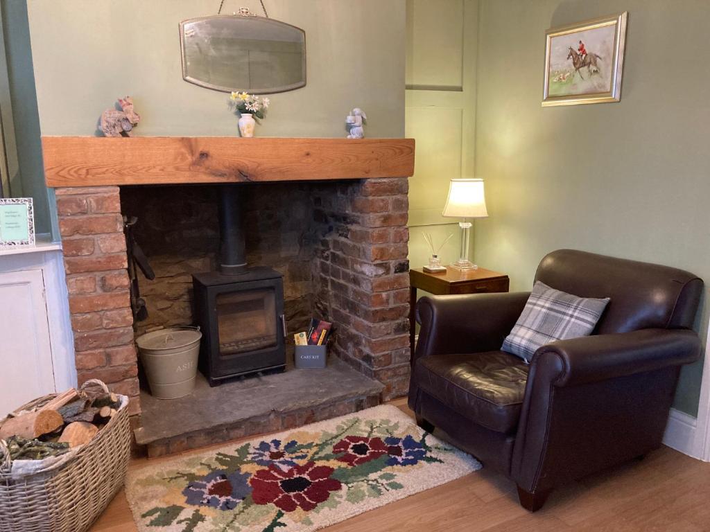 AdlingtonAdlington Cottage, Lancashire的客厅设有壁炉和真皮座椅。