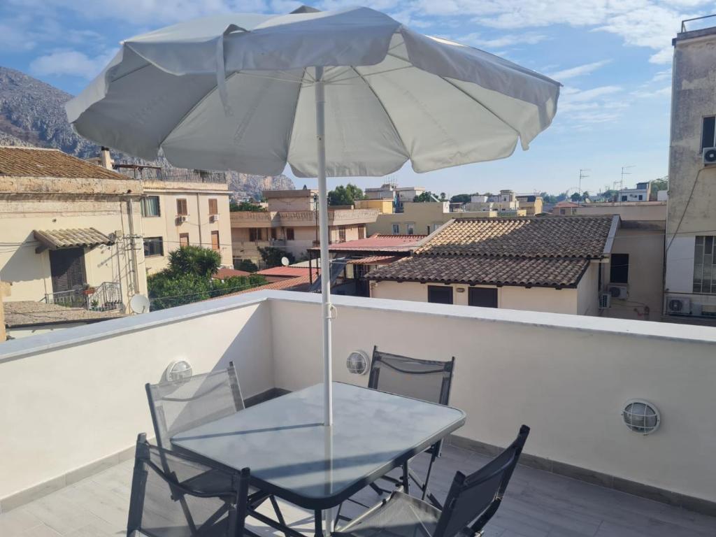 蒙德罗Casetta Bella Nonna Rosetta的阳台配有桌椅和遮阳伞