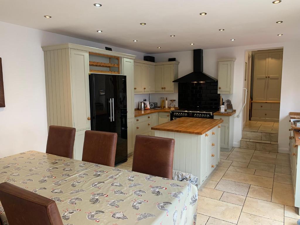 TettenhallStable Cottage的厨房配有桌子和黑冰箱。