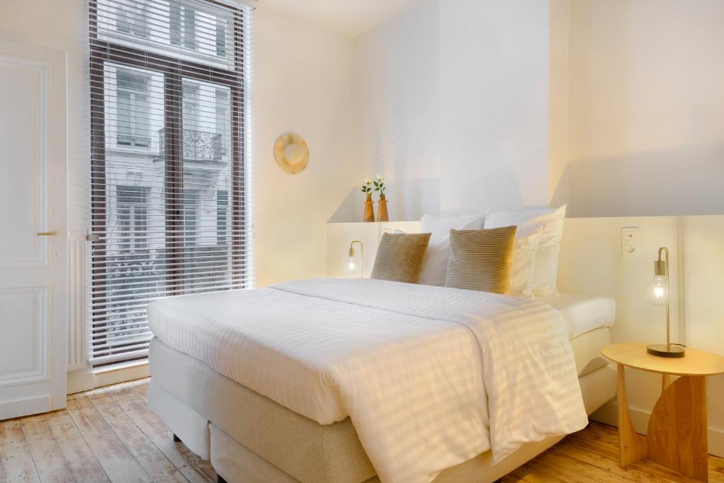 安特卫普The 1894 Residence by Domani Hotels的白色的卧室设有一张大床和一个窗户