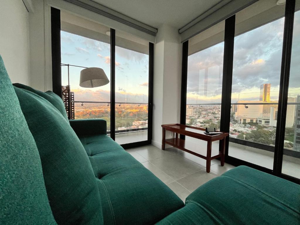 圣何塞Luxury apartment in San José的客厅设有绿色沙发和大窗户