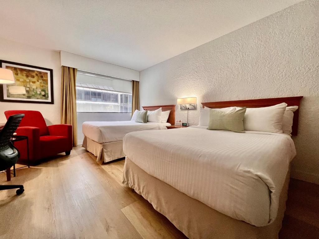 蒙特利尔蒙特利尔大学酒店的酒店客房,设有两张床和一张红色椅子