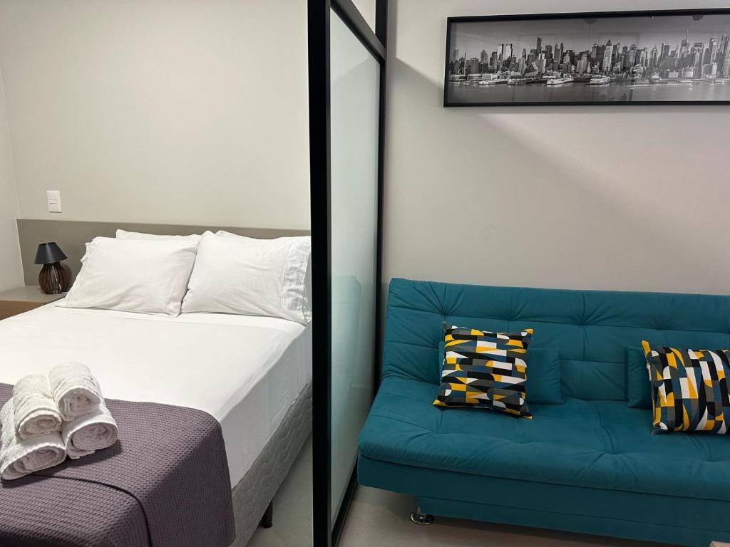 贝洛奥里藏特LOFTS CARIJOS CENTRO BH的一间卧室配有一张床和一张蓝色的沙发