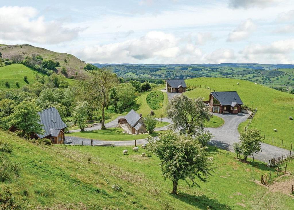 LlandinamSlate House Lodges的享有山丘上带房屋的农场的空中景致