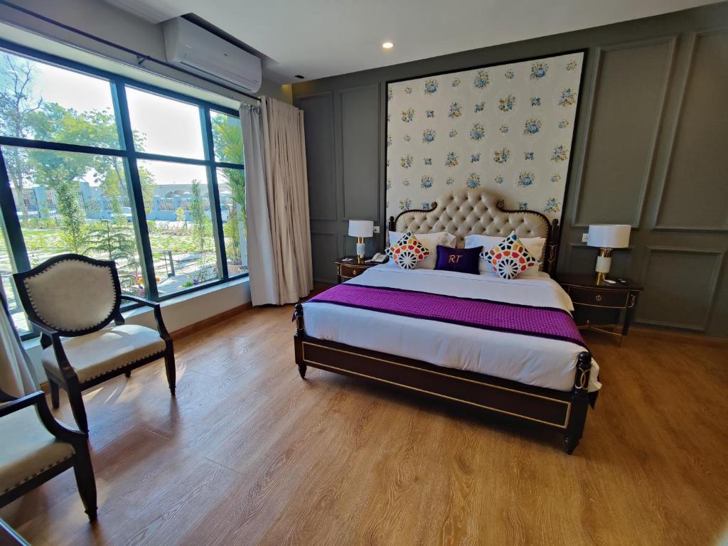 卡拉尔哥特RT Grace Royal Taj Hotel Sukkur的一间卧室配有一张床、一把椅子和窗户。