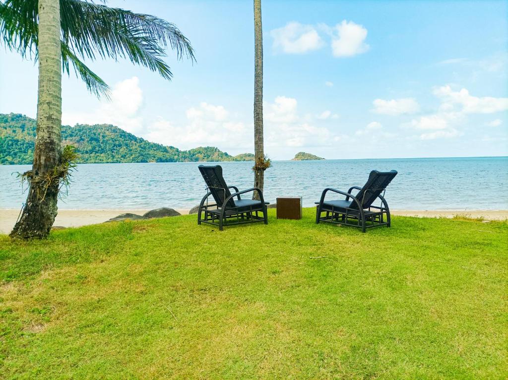 象岛Vitamin sea villas Koh Chang的两把椅子坐在海滩旁的草地上