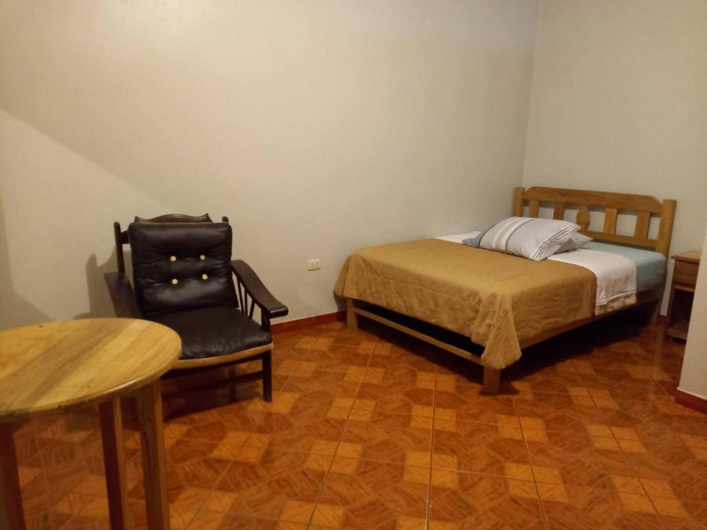 万卡约Hospedaje TOSCANO SUITES的一间卧室配有一张床、一把椅子和一张桌子