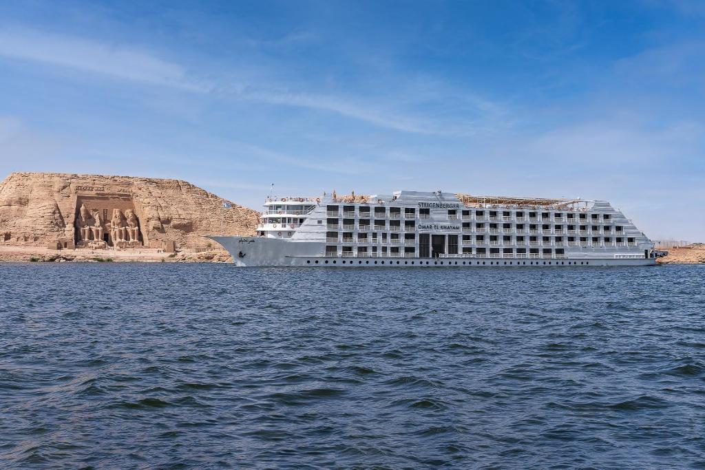 阿斯旺Steigenberger Omar El Khayam Nile Cruise - Every Monday from Aswan for 07 & 04 Nights - Every Friday From Abu Simbel for 03 Nights的建筑物旁边的水中游轮