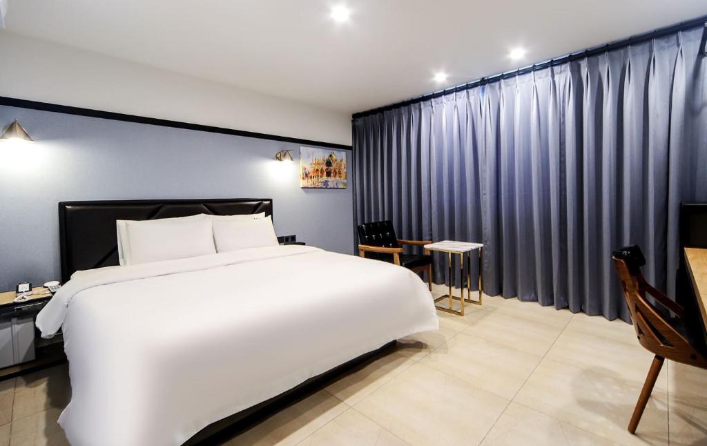 釜山ON:NA Hotel的卧室配有一张白色的大床和一张桌子