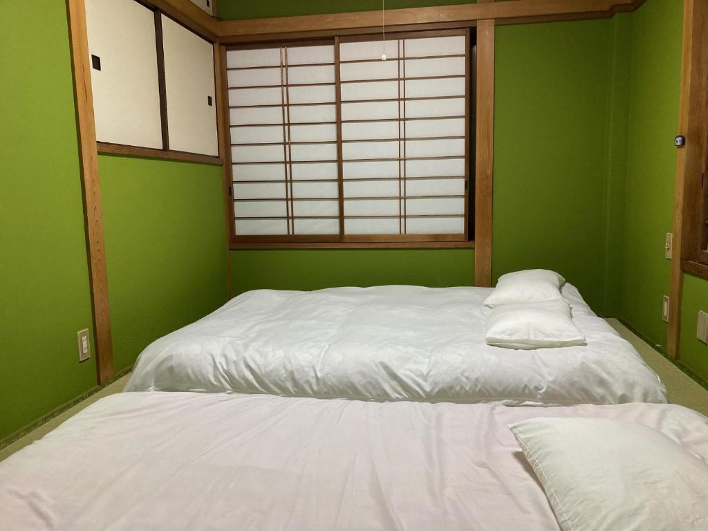 东京Sky Tree INN Ⅱ（晴樹宿Ⅱ）的绿色的客房设有一张带白色床单的床和一扇窗户。