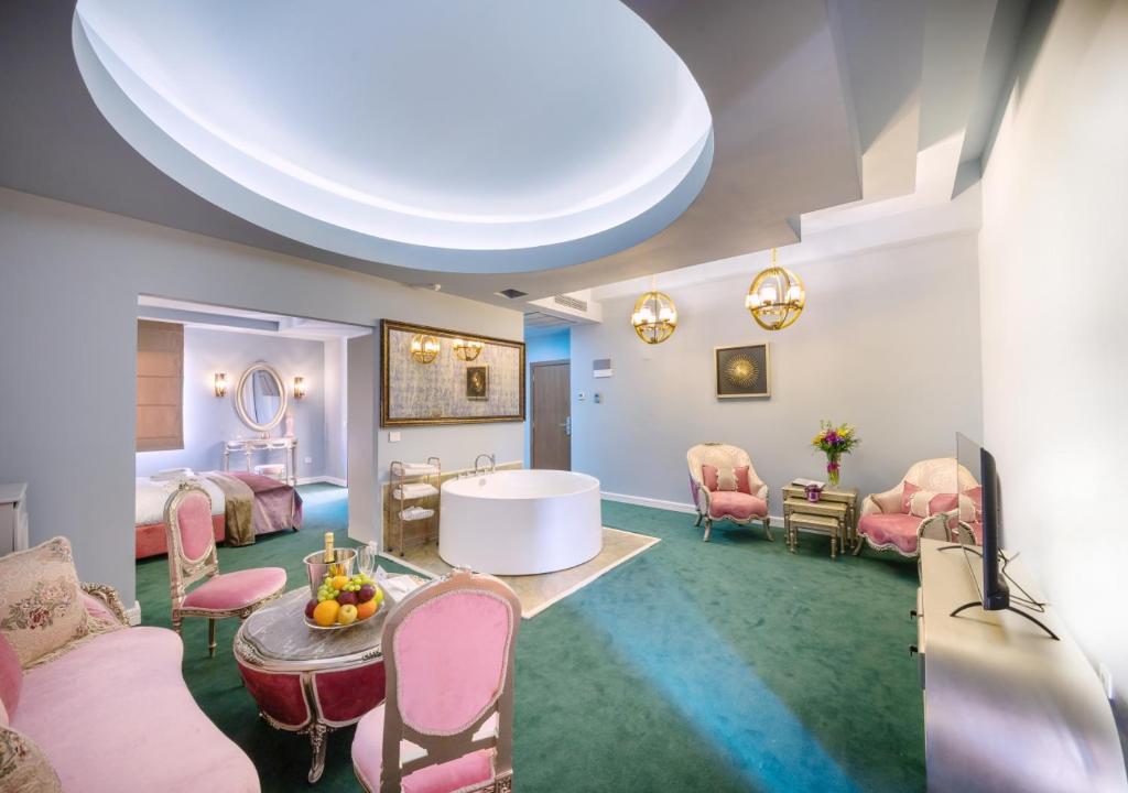 布加勒斯特Phoenicia Comfort Hotel的大房间设有粉红色的椅子和桌子