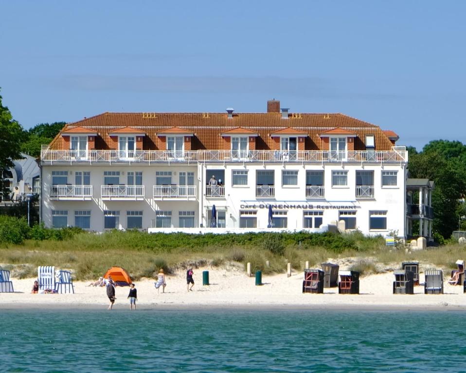 朱列斯拉赫Strandhotel Dünenhaus的海滩上一座大型建筑,海滩上的人