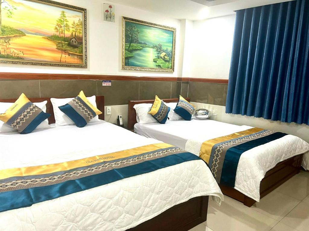 胡志明市Gia Hân Hotel的配有蓝色窗帘的客房内的两张床