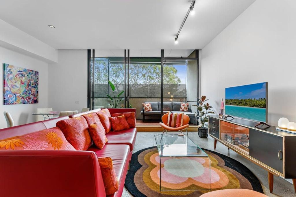 墨尔本Vibrant 2-Bed Apartment Near St Kilda Beach的客厅配有红色的沙发和玻璃桌